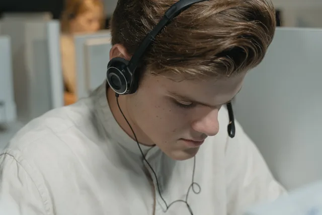 A call center agent wearing headphones focuses on providing customer support in an office setting. Monitoring integration delays that affect agents